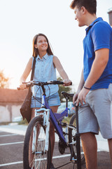 Teenager boy inflating bike tire to help his female friend, outdoor summer photo