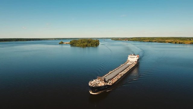 Aerial view:Barge with cargo on the river. River, cargo barge, highway with cars.. Cargo ship on the river.4K, aerial footage.