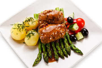     Wrapped pork chops with potatoes and asparagus on white background 