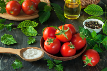 Fresh tomatoes  on a black wooden background with spices.