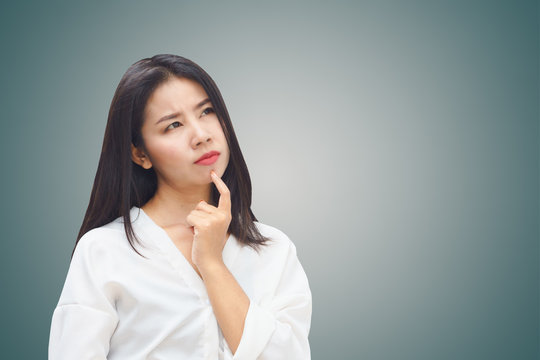 portrait of beautiful Asian business woman thinking look at copy space over grey wall background 