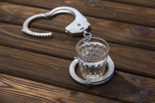 Glass of alcohol with handcuffs. A glass of vodka drinking and driving