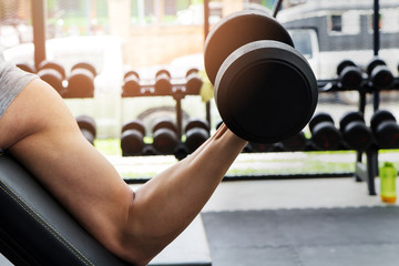 Athlete man training in the gym. A man lifting dumbbell - dumbbell biceps curl