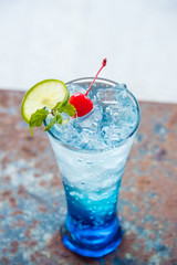 Blue italian soda with cherry on top in high shape glass