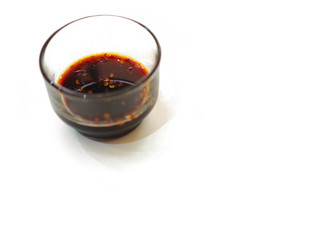 Perspective sour spicy soy with chili black dipping sauce in glass cup, white background