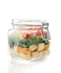 caesar salad in glass jar on white background