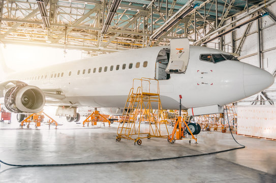 Airliner aircraft in a hangar with an open gate to the service.