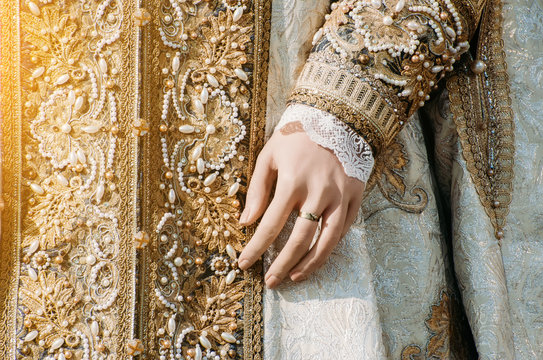 Clothes of a historical imperial woman with pastel tones, a hand with a ring with a precious stone