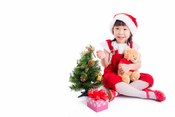 Little asian cute girl wearing santa dress sitting on the floor with christmas tree