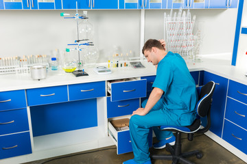 Young lab assistant is looking for something in a cases in a laboratory