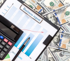 Clipboard with business graphs, calculator and pen on the US dollar background.