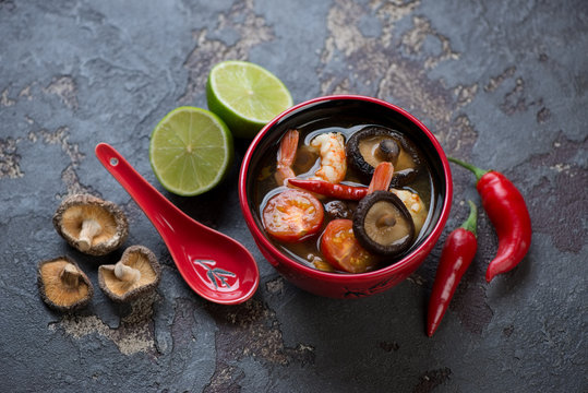 Thai Tom Yum soup with some of its cooking components on a brown stone background, studio shot