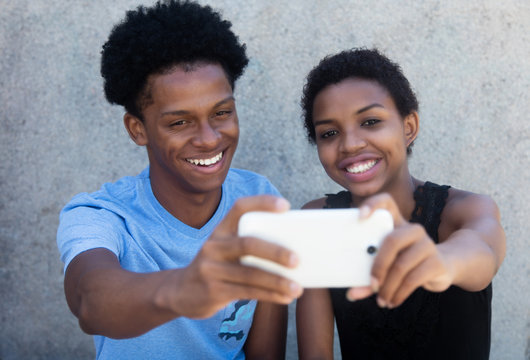 Joyful laughing african american couple taking selfie with phone
