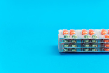 Stack of blisters with pills on the blue background.