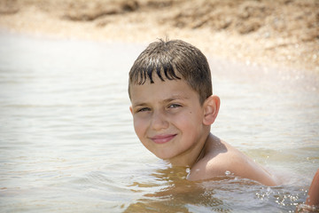In summer, a boy is swimming on the sea. Close-up.