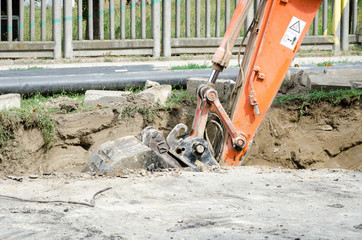 Bulldozer excavator machinery digging a ditch on the street for the new pipeline