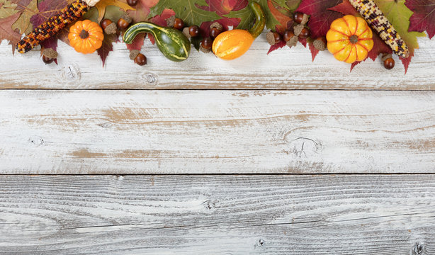 Top border of Autumn foliage with other fall decorations on white rustic wooden boards