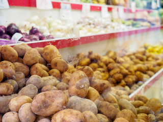Stack of potatoes behind glass window of supermarket, Valencia, Spain