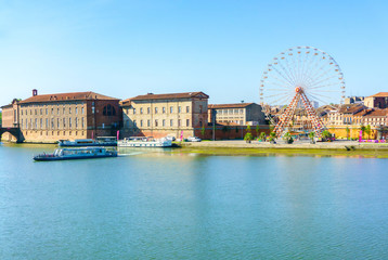 Fototapeta na wymiar Ferris Wheel and view of Saint-Pierre Bridge over Garonne river and Dome de la Grave in Toulouse, France
