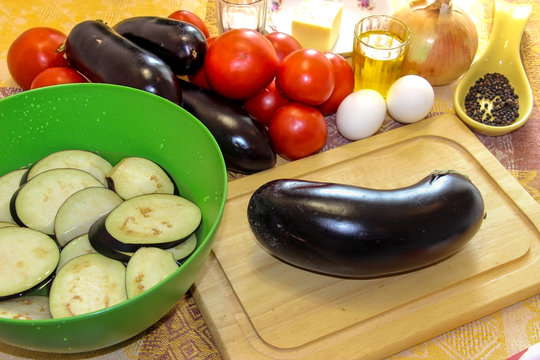 Sliced eggplant on a cutting board and soaked in salted water in a bowl. Fresh vegetables for cooking light dinner, Moussaka - a traditional Greek dish step by step cooking process