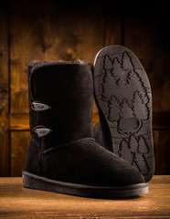 Modern winter suede boots. Pair of winter footwear, one boot standing and showing sole.