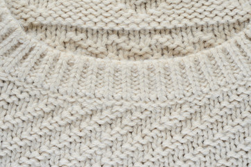 Texture of a beige knitted sweater. Element of a collar on a knitted product close-up