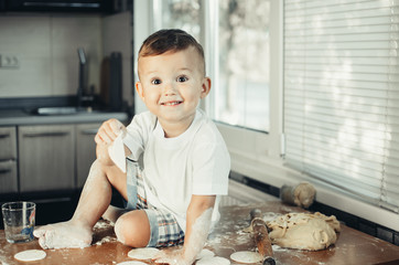 Fototapeta premium A small child sitting on a table covered in flour