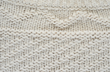 The texture of a knitted sweater is a thick beige string. Part of a sweater with various kinds of...