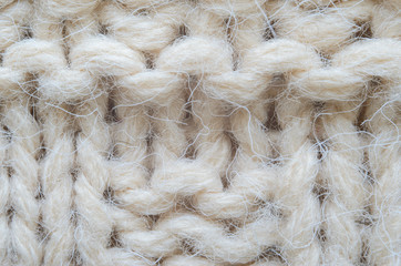 The texture of fabric thick beige sweater close-up. Knitted texture background