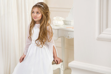 beautiful girl little princess long hair, curly and amazing blue eyes in communion dress and tiara...