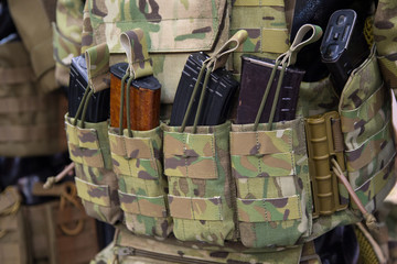 Camouflaged vest with MOLLE system and magazines.
