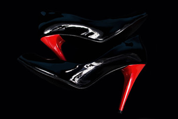 Black stiletos with red heels on black background