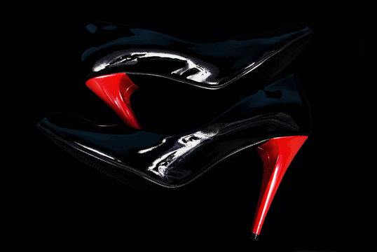 Black stiletos with red heels on black background