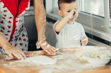 Little boy with mom in the kitchen preparing dough