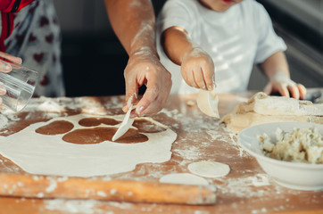 Little boy with mom in the kitchen preparing dough