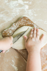 Fototapeta premium A child cuts the raw dough