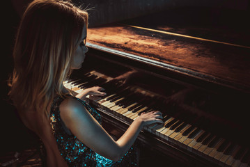 Beautiful woman with fancy elegant dress posing in the piano room