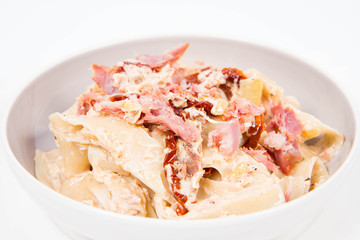 Pappardelle with cream, sun-dried tomatoes and smoked fish on a white background