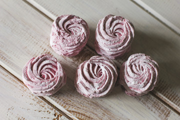 The pink zephyr on white wooden background. The view from top