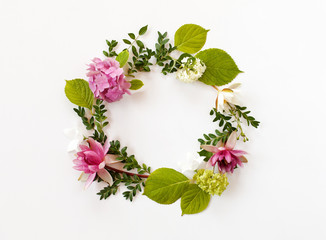 round frame with blooming flowers and leaves on white background. flat lay, top view