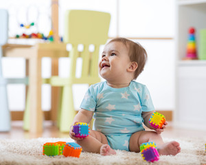baby boy playing with toys at home or kindergarten