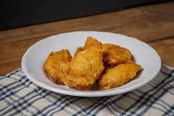 Fried chicken wings on a white plate, on a wooden table.