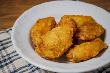 Fried chicken wings on a white plate, on a wooden table.