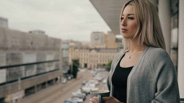 Woman in a cafe drink coffee or latte standing on balcony