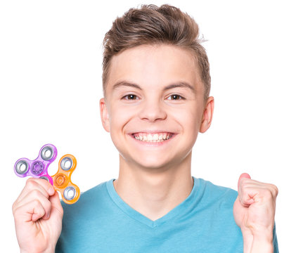 Young teen boy holding popular fidget spinner toy - close up portrait. Happy smiling child playing with Spinner, isolated on white background.