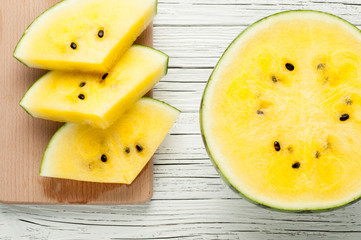 yellow watermelon slices on white wooden background top view
