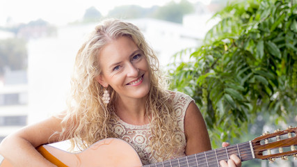 Junge Frau lächelt und spielt Gitarre. 