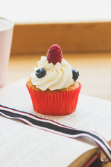 Cupcake with raspberry and blueberry, cup of hot cappuccino