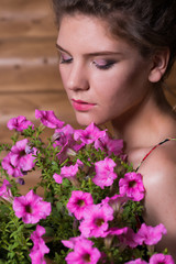 Naklejka premium Beautiful young woman holding a pot of ampel Petunia flowers