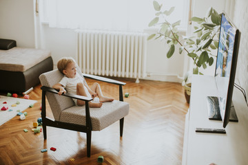 Little boy sitting on armchair and watching television